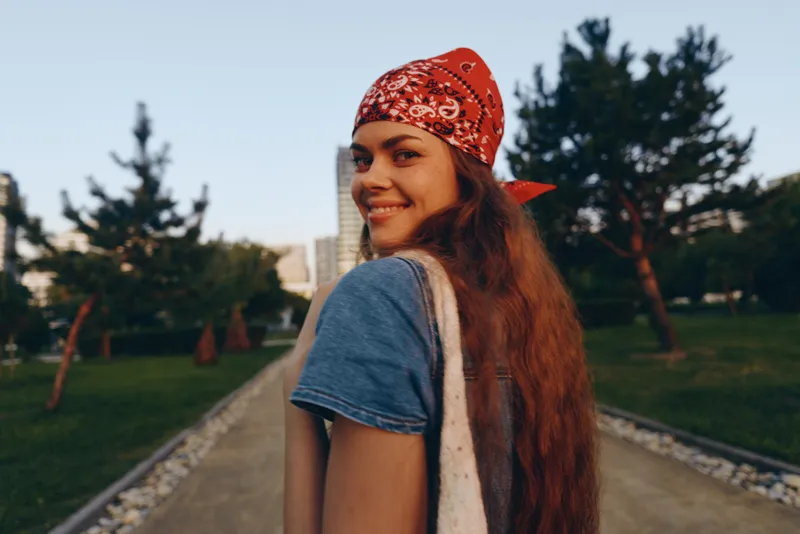 lifestyle woman wearing modern boho-western denim street style with a red bandana smiling outdoors in film color natural light