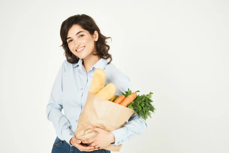 Женщина с пакетом продуктов, овощами, в супермаркете совершает покупки