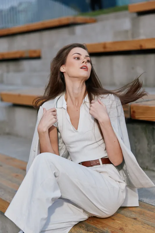 woman fashion portrait in light outfit posing outdoors with confident expression and natural background autumn style