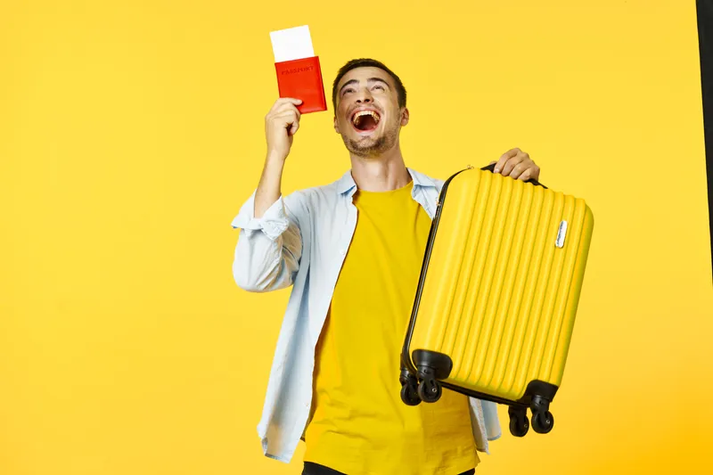 Счастливый мужчина с красным паспортом и чемоданом в руке смотрит вверх