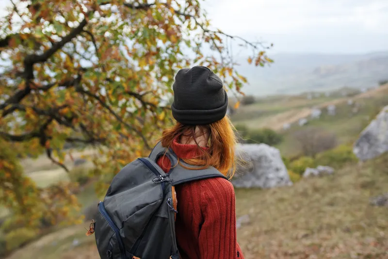 Женщина-туристка с рюкзаком путешествует по горам, наслаждаясь природой и активным образом жизни