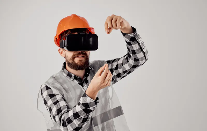 Строитель в оранжевой каске и 3D-очках жестикулирует руками