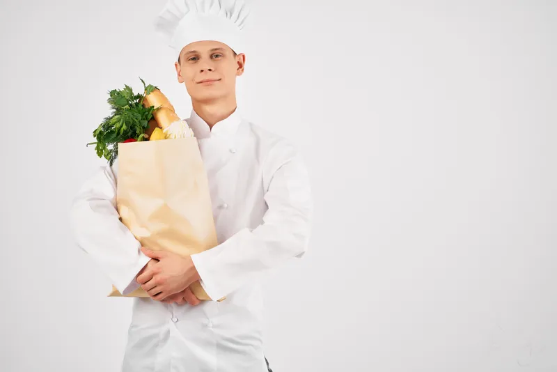 Мужчина в униформе повара с упаковкой продуктов жестикулирует рукой, здоровая еда на кухне