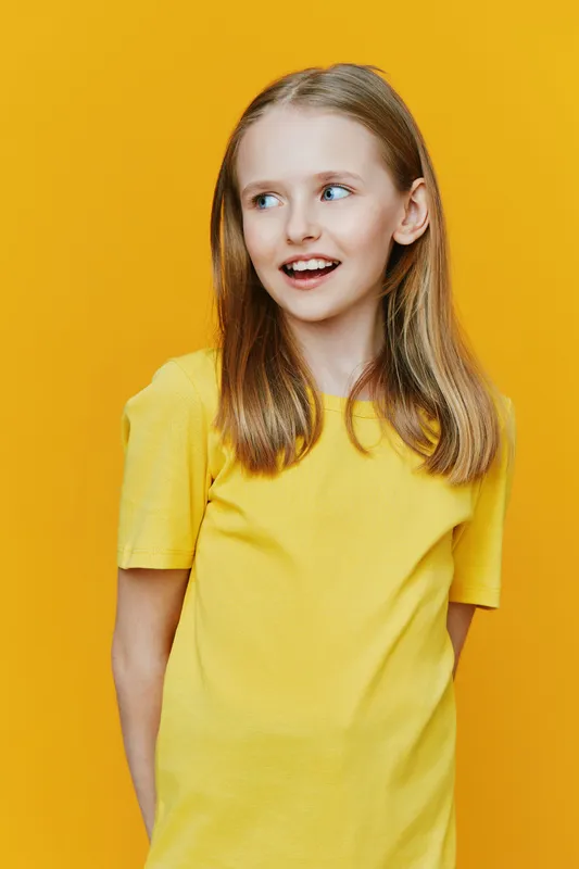 Joyful young girl in a bright yellow t shirt against a vibrant yellow background, exuding happiness and playfulness, perfect for family or children s themes