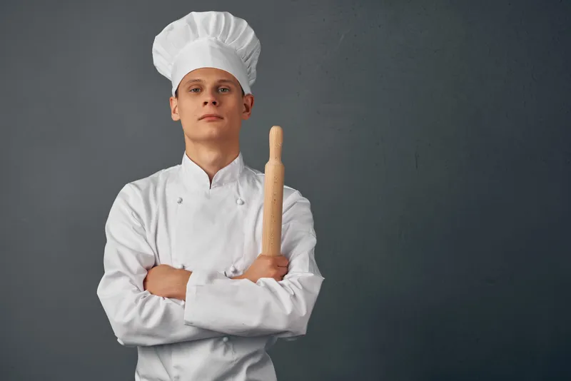 Мужчина в форме шеф-повара работает на кухне ресторана, занимаясь приготовлением пищи