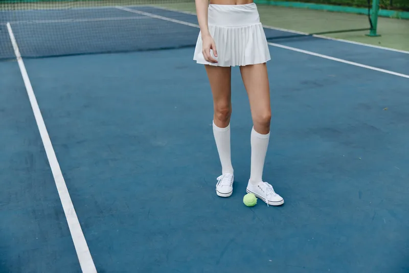 Young athletic woman in a sporty outfit on a tennis court, showcasing enthusiasm for fitness and sports, with a vibrant blue court background