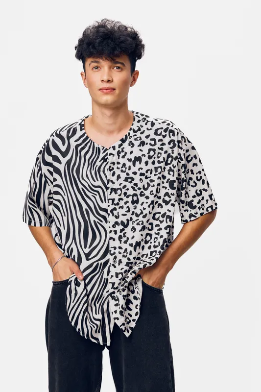 young man wearing black and white animal print t-shirt with hands in pockets posing against white background, casual style, confident expression