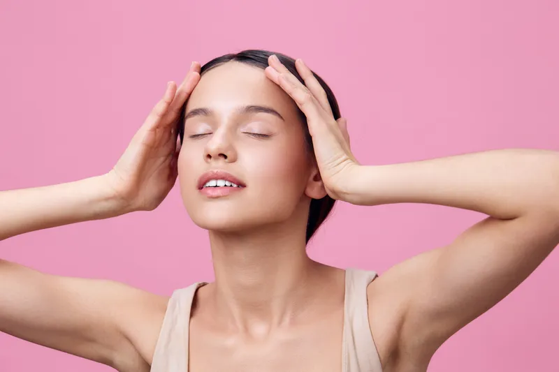 Young woman with closed eyes practicing mindfulness against a pink background, expressing calm and relaxation in a minimalist style