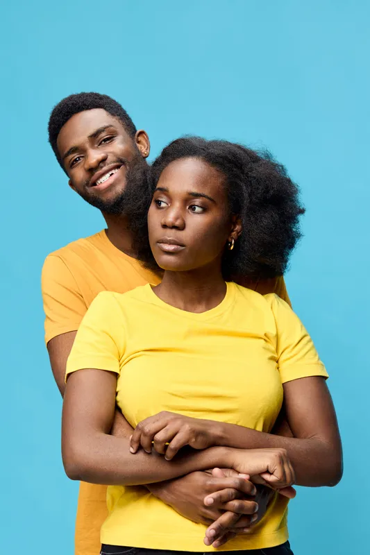 Happy couple embracing against a bright blue background, wearing yellow t shirts, showcasing love and joy in a vibrant, seasonal atmosphere