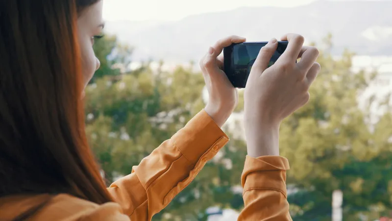 Женщина с телефоном в руке фотографирует природу на камеру во время отпуска на фоне пейзажа