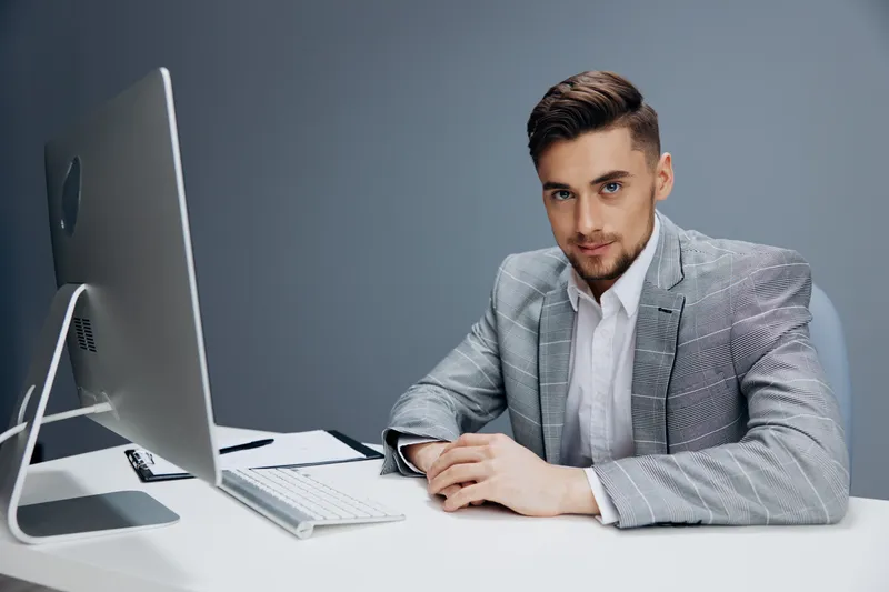 Менеджер работает за компьютером в офисе на сером фоне