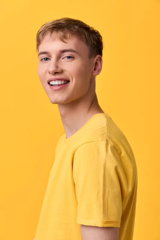 Smiling man in a bright yellow shirt stands against a bold yellow backdrop, conveying positivity, casual style, and approachable energy for lifestyle, fashion, and promotional visuals