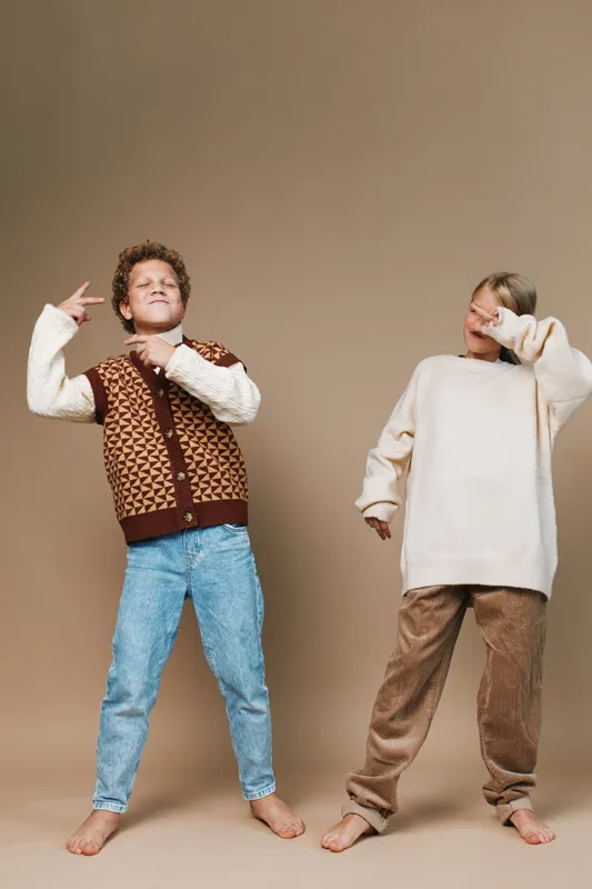Two playful boys pose in casual outfits against a neutral backdrop, exuding confidence and carefree energy with relaxed stance and bright, soft lighting.