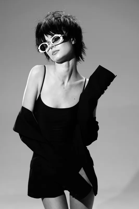 Stylish woman posing in black dress with sunglasses in black and white glamour portrait with chic vibe.