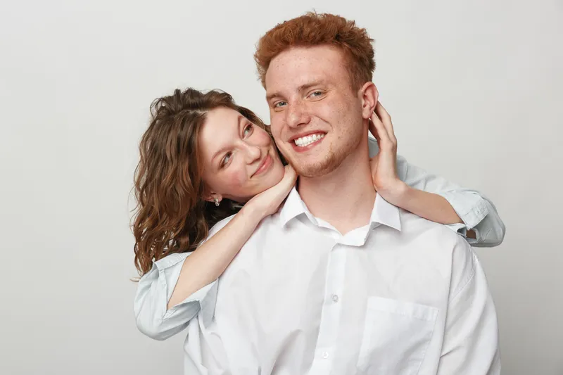 Happy young couple with red hair smiling and embracing each other on white background. Concept of love, relationship, friendship, and positive emotions between people.