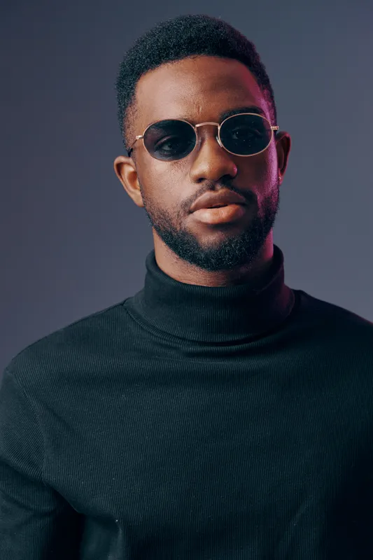 Stylish Black Man in Sunglasses Wearing Turtleneck Sweater Against Dark Gradient Background