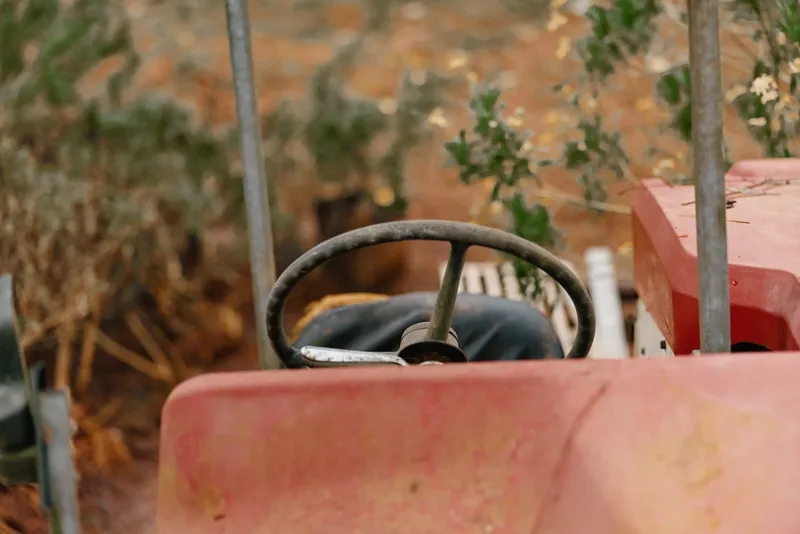 Rustic vintage tractor interior showcasing the steering wheel and worn seat in an autumn landscape, evoking nostalgia for agricultural life