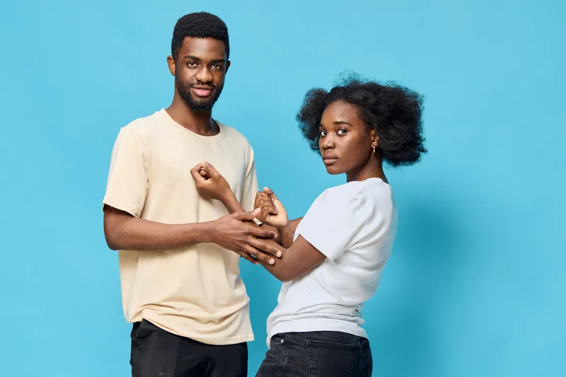 Diverse couple enjoying playful interaction against a vibrant blue background, representing love, joy, and connection in modern relationships