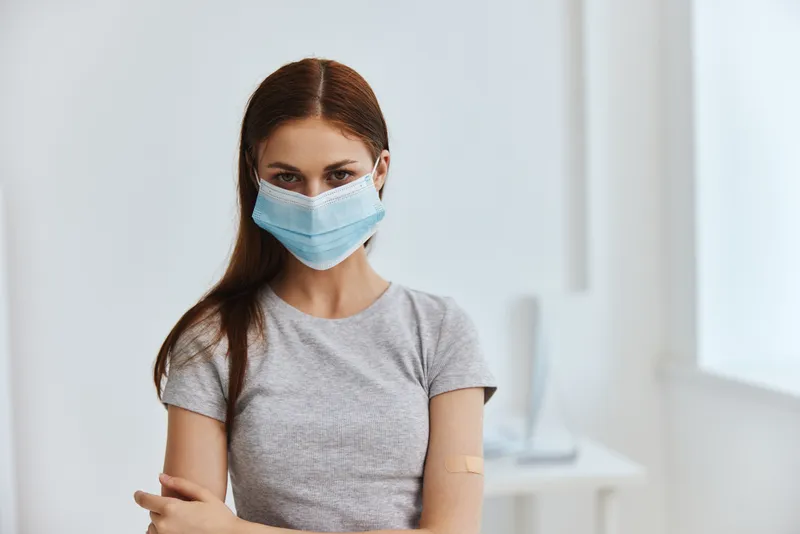 Пациент в медицинской маске держит паспорт здоровья для вакцинации в больнице