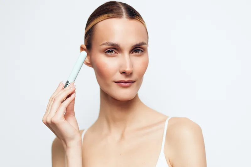 woman skincare beauty portrait serum spa treatment hygiene cream wellness concept, young woman holds skincare device for facial serum application, clean studio background, smooth glowing skin, calm