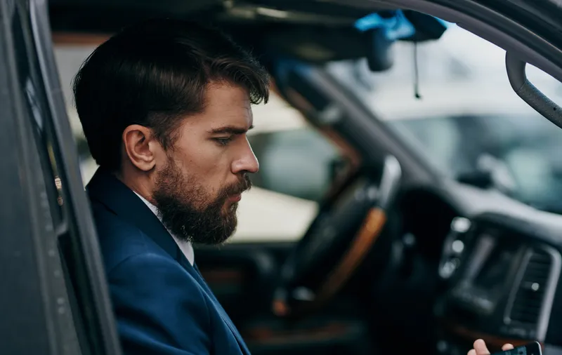 Мужчина в костюме выглядывает из окна автомобиля, весёлая поездка, образ жизни