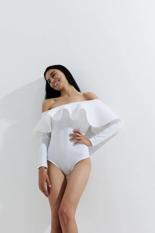 woman sport fitness in white athletic wear posing gracefully against plain white background, showcasing strength and elegance in natural light setting