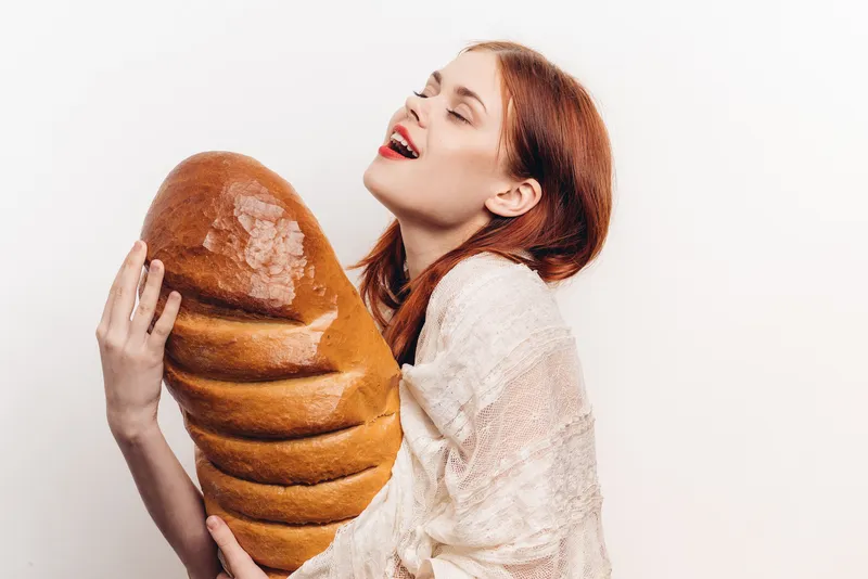 Эмоциональная женщина с большим бутоном, продукт из муки, хлеб на светлом фоне