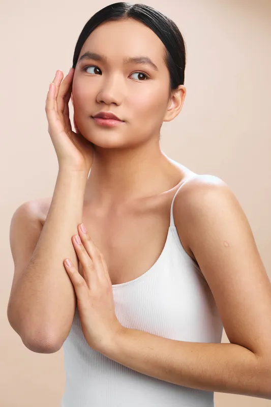 asian woman is photographed in a clean studio setting, gazing softly to the side with a calm, confident expression, suggesting modern poise and a minimal, versatile look for lifestyle or beauty