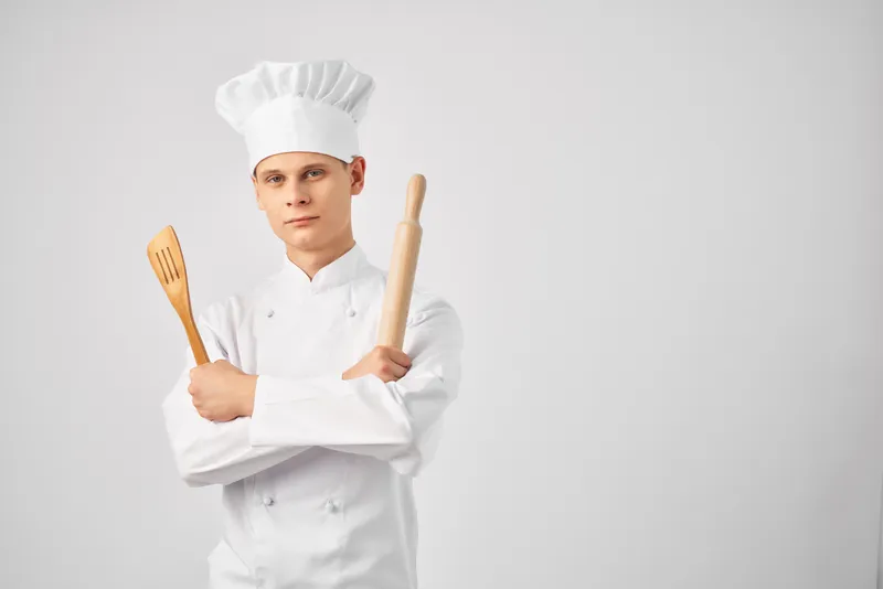 Повар-мужчина, кухонная утварь, приготовление пищи, профессиональная деятельность на светлом фоне
