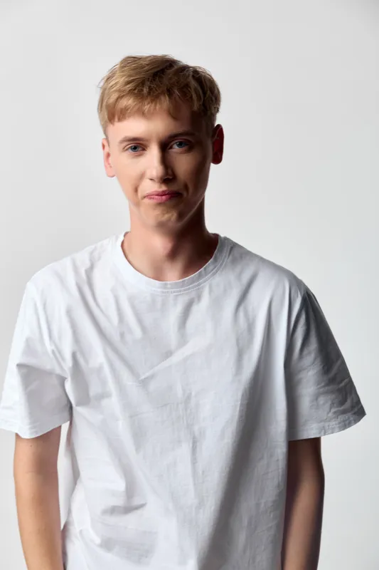 Man in a white shirt stands in a bright studio, casual vibe with relaxed posture, direct gaze and clean background, minimalist wardrobe, lifestyle stock imagery for marketing, social media and