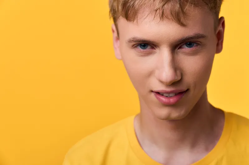Young man close up yellow background yellow shirt facial expression studio lighting clear skin confident look suitable for fashion lifestyle stock and commercial use