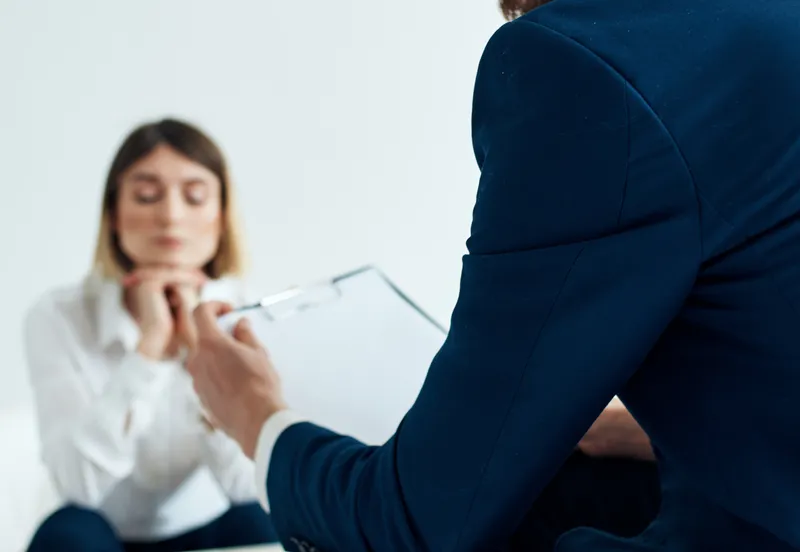 Бизнесмен в синей куртке и женщина на заднем плане за столом
