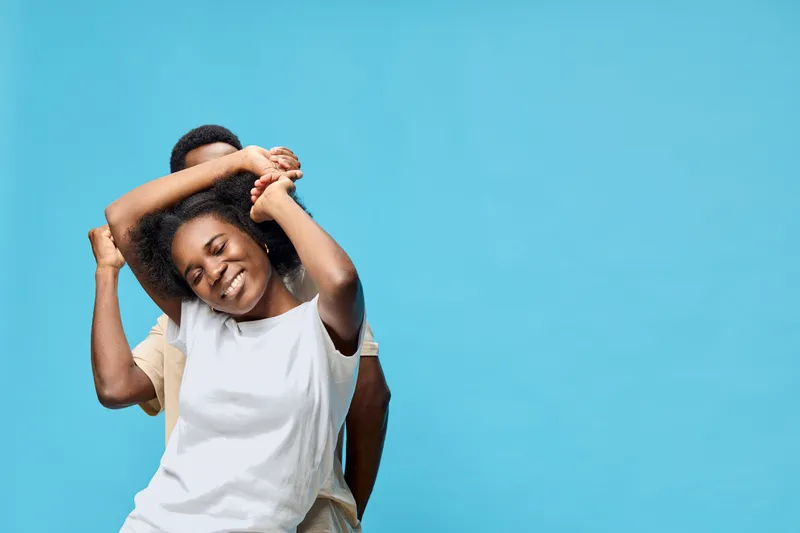 Happy young African couple celebrating together on a blue background, showcasing joy, connection, and love with a bright and uplifting vibe