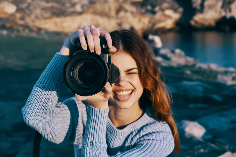 Жизнерадостная женщина-фотограф на открытом воздухе, скалистые горы, профессиональная работа, туризм