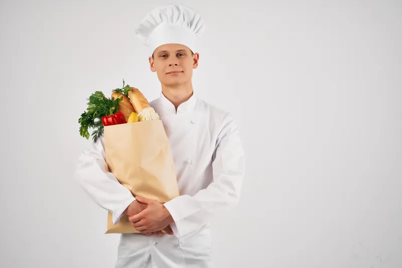 Мужчина-шеф-повар с пакетом продуктов в ресторане, профессионально занимающийся приготовлением пищи