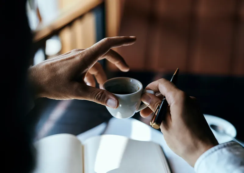 Бизнесвумен в кафе с книгой на столе, документами и чашкой кофе