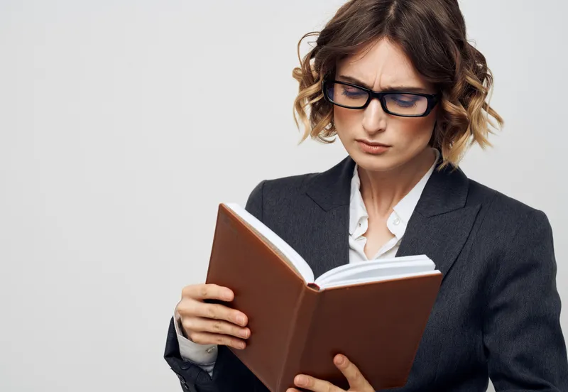 Деловая женщина в классическом костюме с книгой в руках, модель в сфере финансов