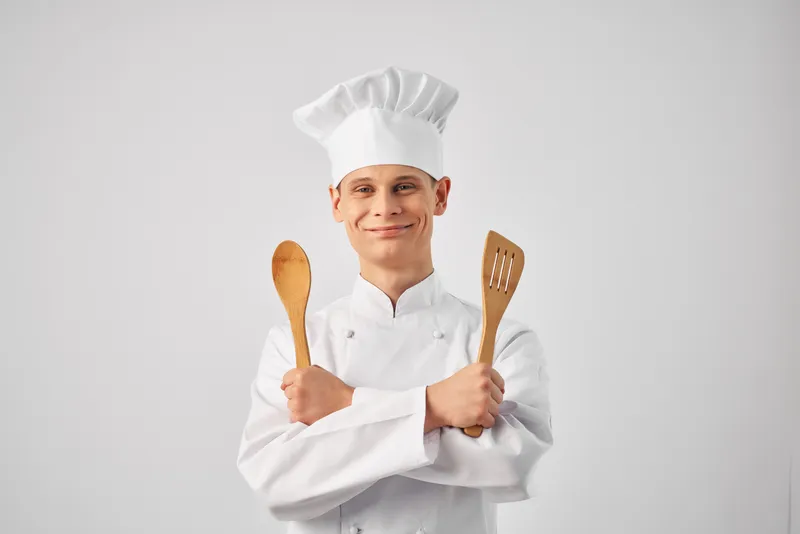 Весёлый шеф-повар-мужчина с кухонной утварью, работающий в ресторане, персонал