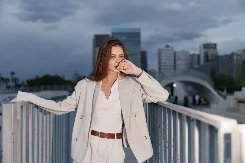 Confident businesswoman in a modern cityscape showcasing professional attire, expressing determination and style, against a backdrop of urban architecture.
