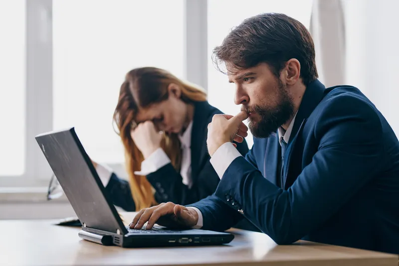 Менеджеры сидят перед ноутбуком, работая в команде через интернет