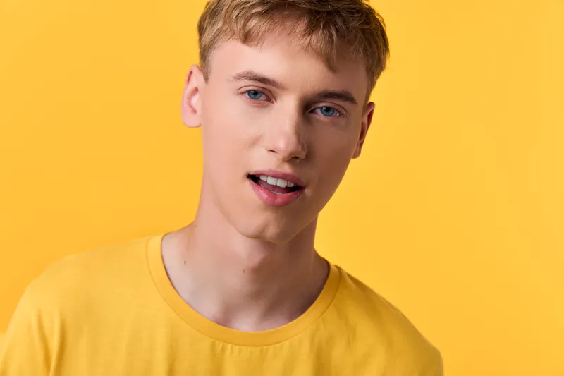 Yellow tee clad young man against bright yellow background, casual fashion vibe for lifestyle and marketing, approachable expression with clean composition and bold color