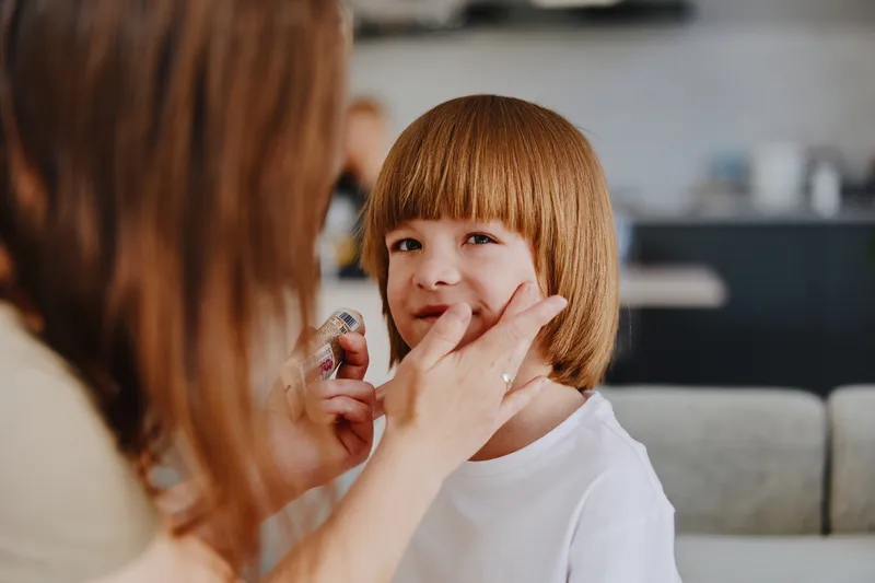 Caring woman applying cream on a child's face, showcasing a moment of tenderness and bonding. This scene captures the essence of nurturing and parental love.