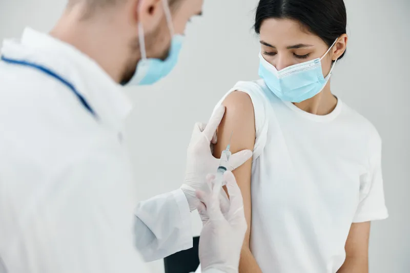 Вакцинация: пациент в медицинской маске в больнице и врач