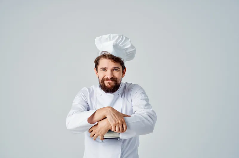 Бородатый шеф-повар мужского пола с кастрюлей в руках на кухне ресторана за работой
