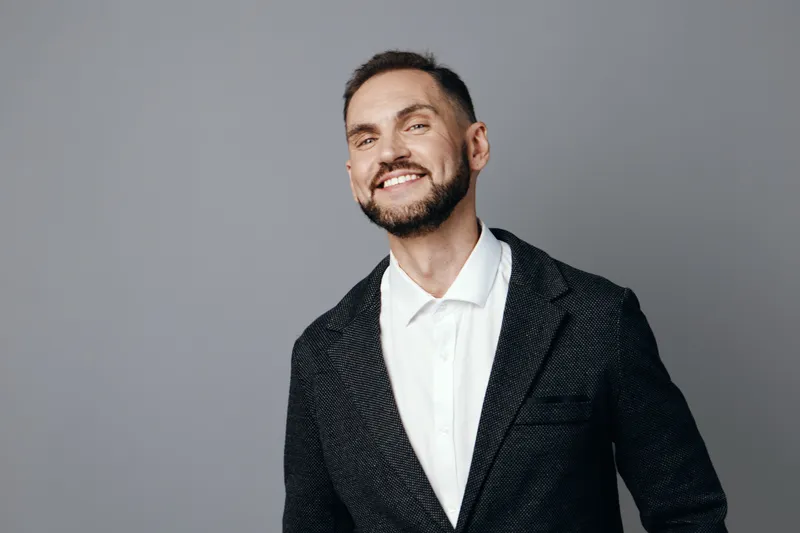 Business professional man with a confident smile stands against an isolated colored background, radiating optimism, approachability, and modern corporate presence.