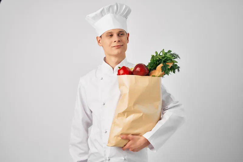Мужчина в форме шеф-повара с упаковкой продуктов для доставки ресторанного сервиса