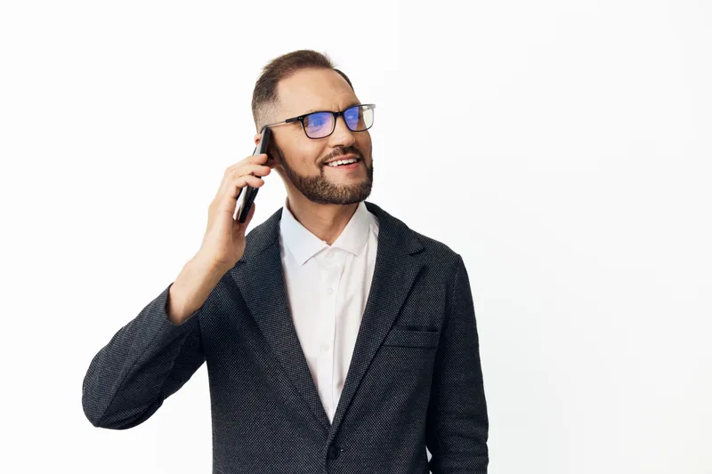 Professional man in business attire speaks on a mobile phone with a confident, focused expression, isolated colored background highlighting corporate communication and executive presence.