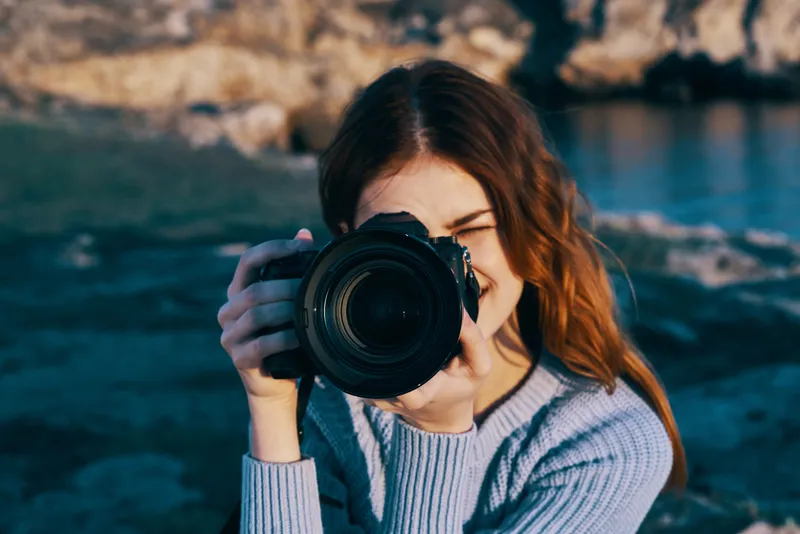 Жизнерадостная женщина-фотограф на открытом воздухе, скалистые горы, профессиональная работа, туризм