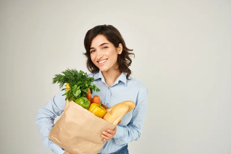 Женщина с пакетом продуктов, здоровой едой, овощами, совершает покупки в супермаркете