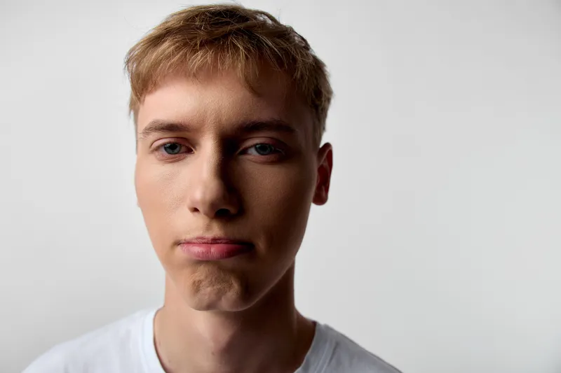 Closeup of a young man making a pouty face, white tee, neutral studio backdrop, expressive mood and humorous expression captured with clean lighting